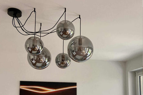 Stylische Deckenlampe mit fünf gläsernen Schirmen und einer modernen schwarzen Aufhängung.