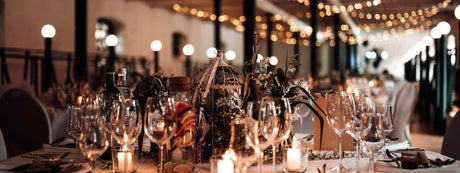 Elegant dekorierter Hochzeitstisch mit Kerzen, Wein und Blumenarrangements unter stimmungsvoller Beleuchtung.