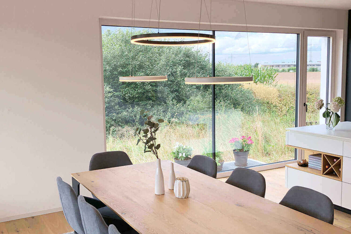 Esszimmer Beleuchtung – diese Möglichkeiten gibt es: Moderne Hängelampen über einem Esstisch in einem hellen Raum.