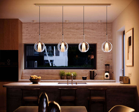 Moderne s.luce Leuchten hängen über einer stilvollen Küche mit Holz- und Steinelementen.