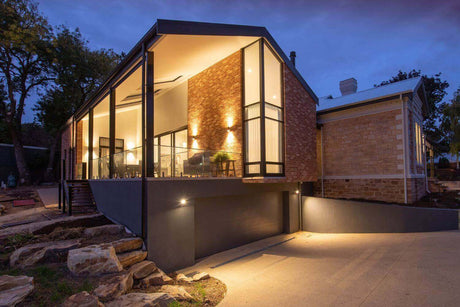 Moderne Hausansicht bei Nacht mit stilvoller Beleuchtung und Glasfassade.