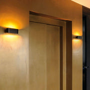 Applique murale OSSA R7s ovale Up & Down noire sur un mur doré, design moderne avec une lumière chaleureuse.