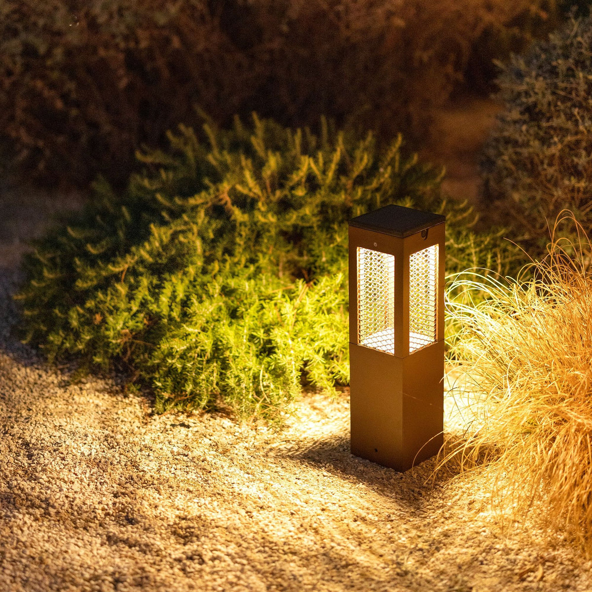 Lampada solare da percorso Tradition H 45 cm in finitura Corten in alluminio, illuminata su un vialetto del giardino tra le piante