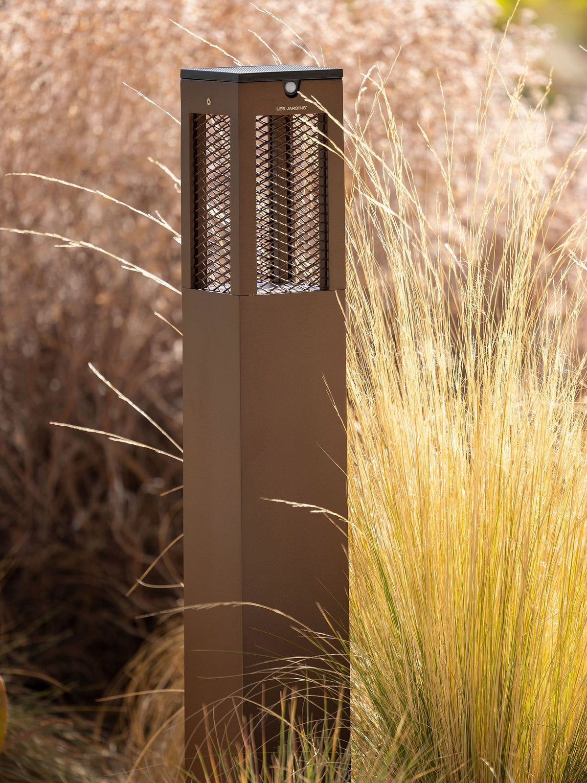 Farola solar para senderos Tradition H 90cm de aluminio Corten con diseño perforado en un entorno de jardín