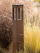 Farola solar para senderos Tradition H 90cm de aluminio Corten con diseño perforado en un entorno de jardín