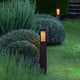 Farola solar para senderos Tradition H 90cm de aluminio Corten con luz cálida en el jardín entre arbustos, vista frontal