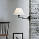 Break vegglampe svart, klar på en vegg med murstein, kombinert med en moderne stol.