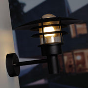 LØnstrup 32 utendørs vegglampe svart på en vegg, avgir mykt lys for utendørs bruk.
