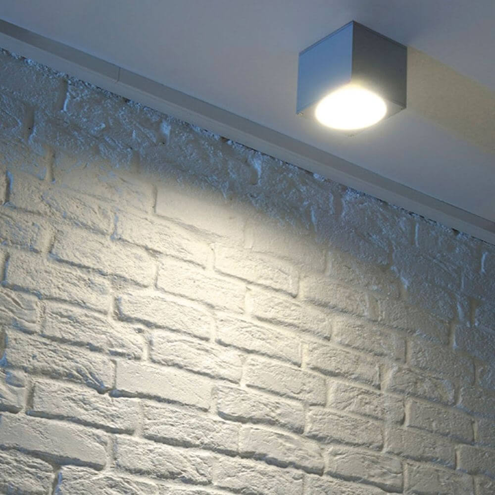 Big Theo Wall Out Wandleuchte eckig silbergrau ES111 max. 75W an einer Wand aus heller Ziegelstruktur.