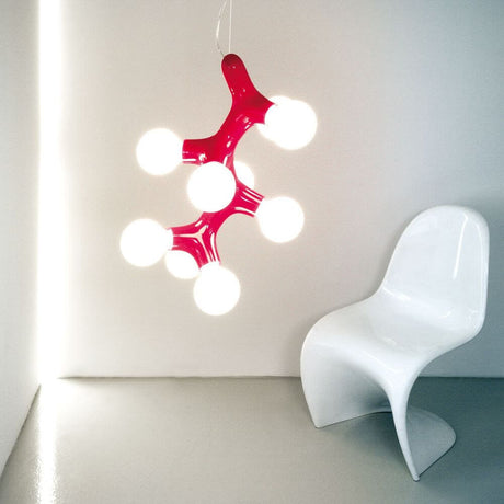 Lampada a sospensione DNA Quattro-9.1 in rame in un ambiente moderno con sedia bianca.