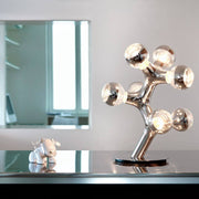 DNA Triple-7 Tafellamp Chrom op tafel met stijlvolle lichtbronnen en modern design.