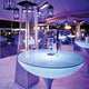 Moree Lounge Table Outdoor Tisch 75cm bei Nacht, beleuchtet unter einem Zelt mit Lampen und Gläsern.