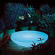 Moree Lounge Variation Outdoor LED Tisch oder Wandleuchte in einem blühenden Garten bei Nacht.