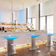Moderne Bar mit beleuchteten Theken und eleganten Hockern in einem stilvollen Innenraum.