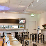 Einladendes Restaurant mit warmer 3000K Beleuchtung und stilvollen Holztischen.