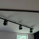 3-Phasen T-Verbinder links in Schwarz für Stromschienen,ermontiert mit modernen Spots an der Decke.