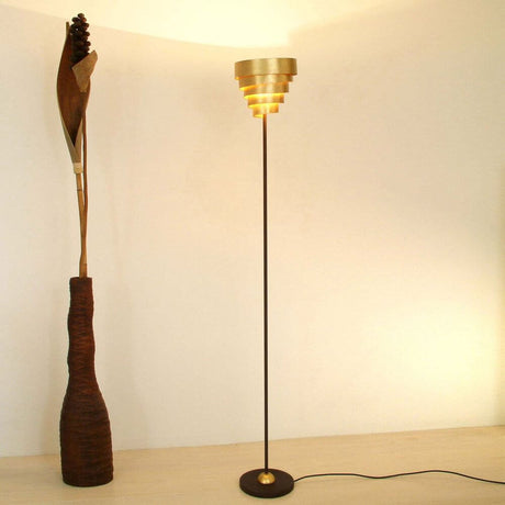 Candeeiro de pé Banderole em ferro castanho-preto-dourado com design moderno e iluminação elegante.