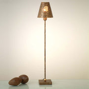 Lampe de table Gancio Groß en fer brun or antique sur une table moderne avec des boules décoratives.