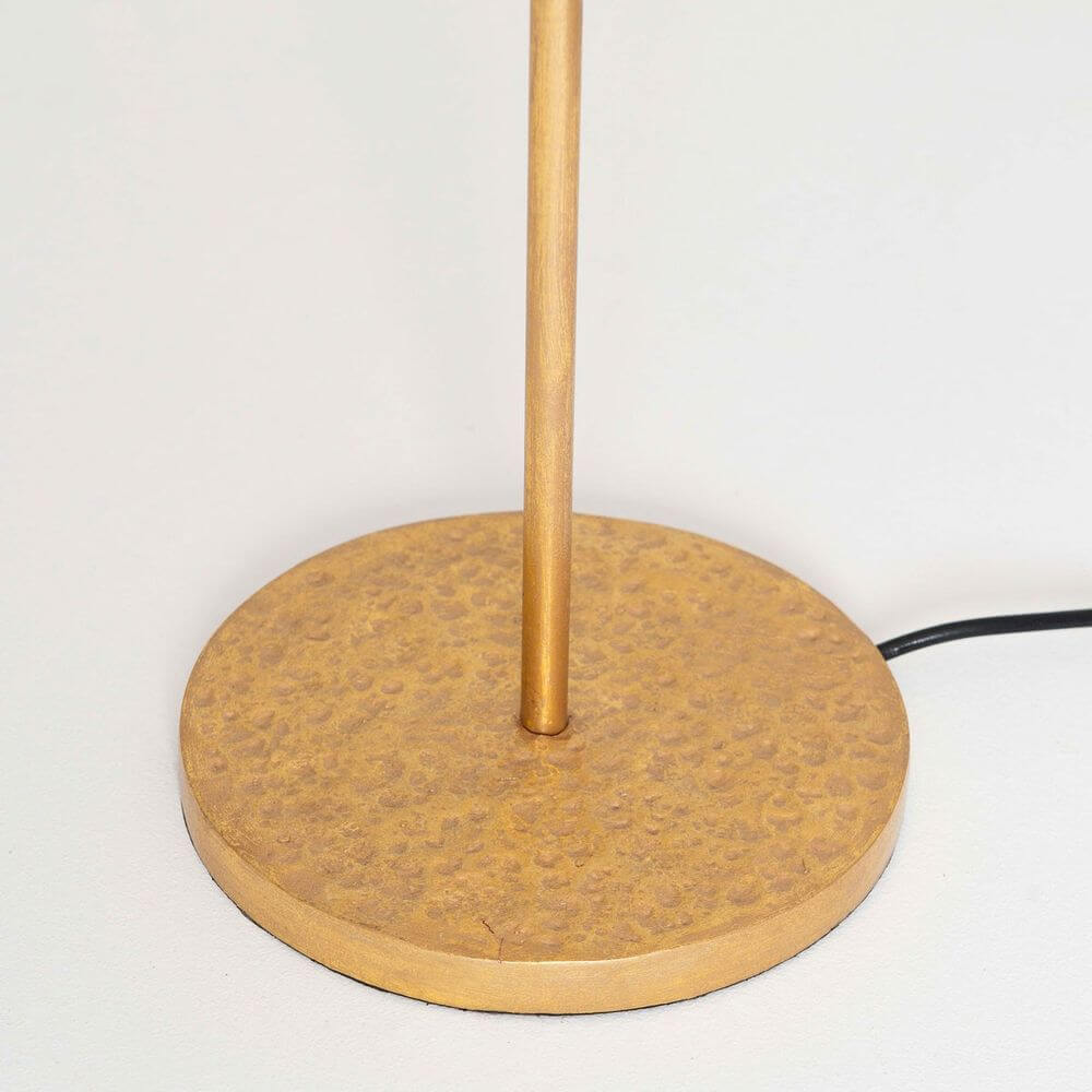 Stehleuchte Mattia Rund Eisen Gold-Schwarz, Sockel der Lampe unscharf auf hellem Hintergrund abgebildet.