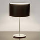 Tischleuchte Mattia Oval Eisen Silber-Schwarz auf einem Tisch, modernes Design mit schwarzem Lampenschirm.