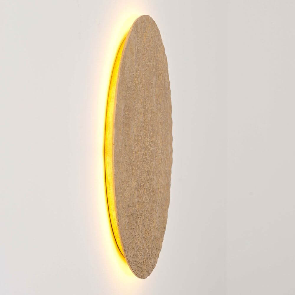 Wandleuchte Meteor Eisen Gold an der Wand, ovales Design mit warmem Lichtschein.
