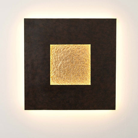 Applique murale Eclipse Gross en fer brun-noir-or sur un mur avec une lumière chaude et une surface de détail dorée.