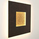 Wandleuchte Eclipse Gross Eisen Braun-Schwarz-Gold mit stilvollem, beleuchtetem Quadrat im Hintergrund.