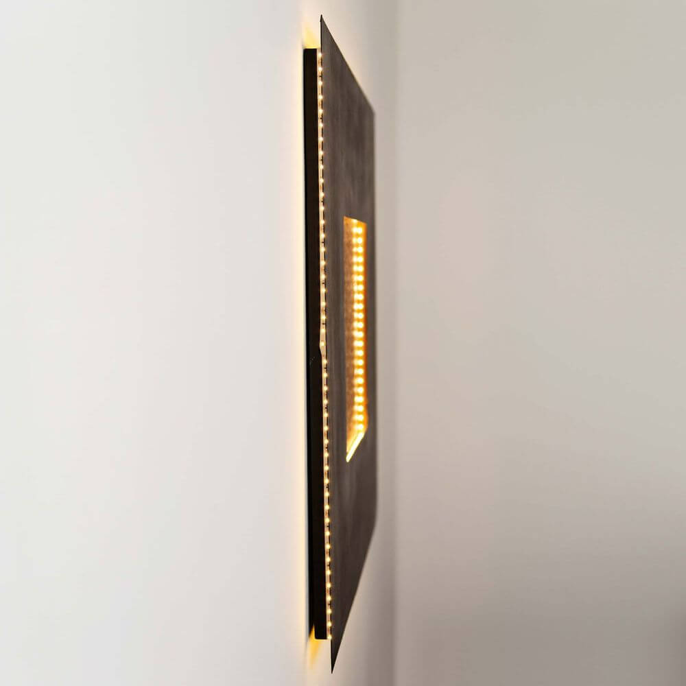Wandleuchte Eclipse Gross Eisen Braun-Schwarz-Gold an einer Wand, moderner Leuchtenstil mit warmem Licht.