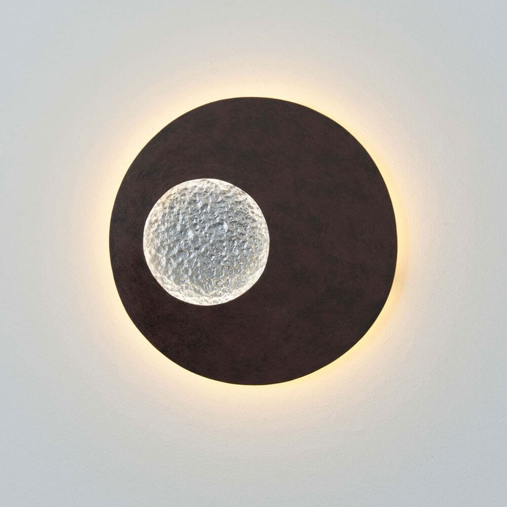Wandleuchte Luna Rund Klein Eisen Braun-Schwarz-Silber an der Wand mit einem leuchtenden, runden Design.