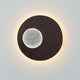 Wandleuchte Luna Rund Klein Eisen Braun-Schwarz-Silber an der Wand mit einem leuchtenden, runden Design.