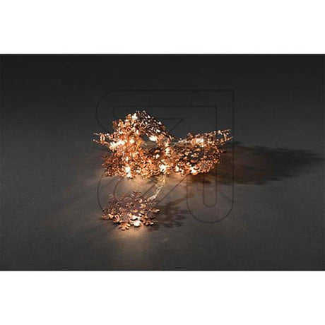 LED Dekolichterkette kupferfarbene Metallschneeflocken auf dunklem Hintergrund, mit warmem Licht.