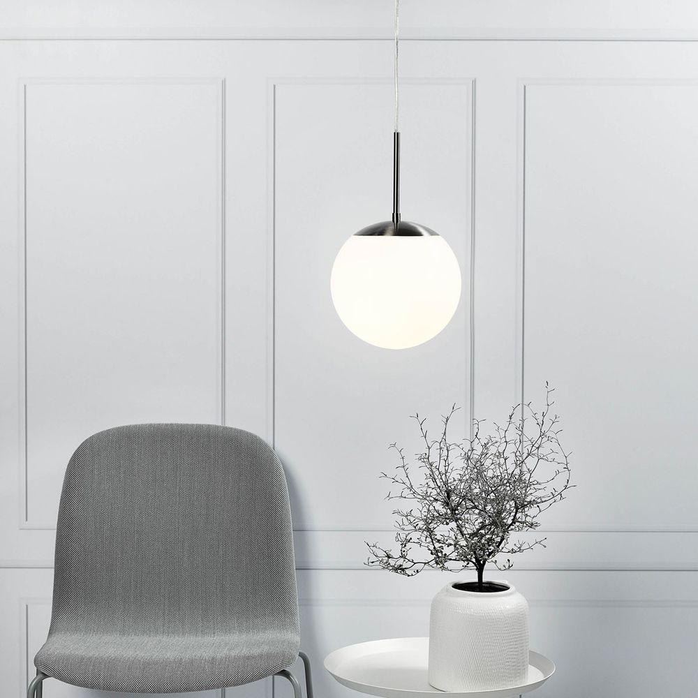 Moderne Pendelleuchte in Weiß über einem eleganten Tisch mit Pflanze und Stuhl, elegantes Design für Küchenbereich.