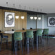 Moderne Einrichtung mit 3er-Hängeleuchte Mine Space Dunkelgrau über einer eleganten Bar mit grünen Stühlen.