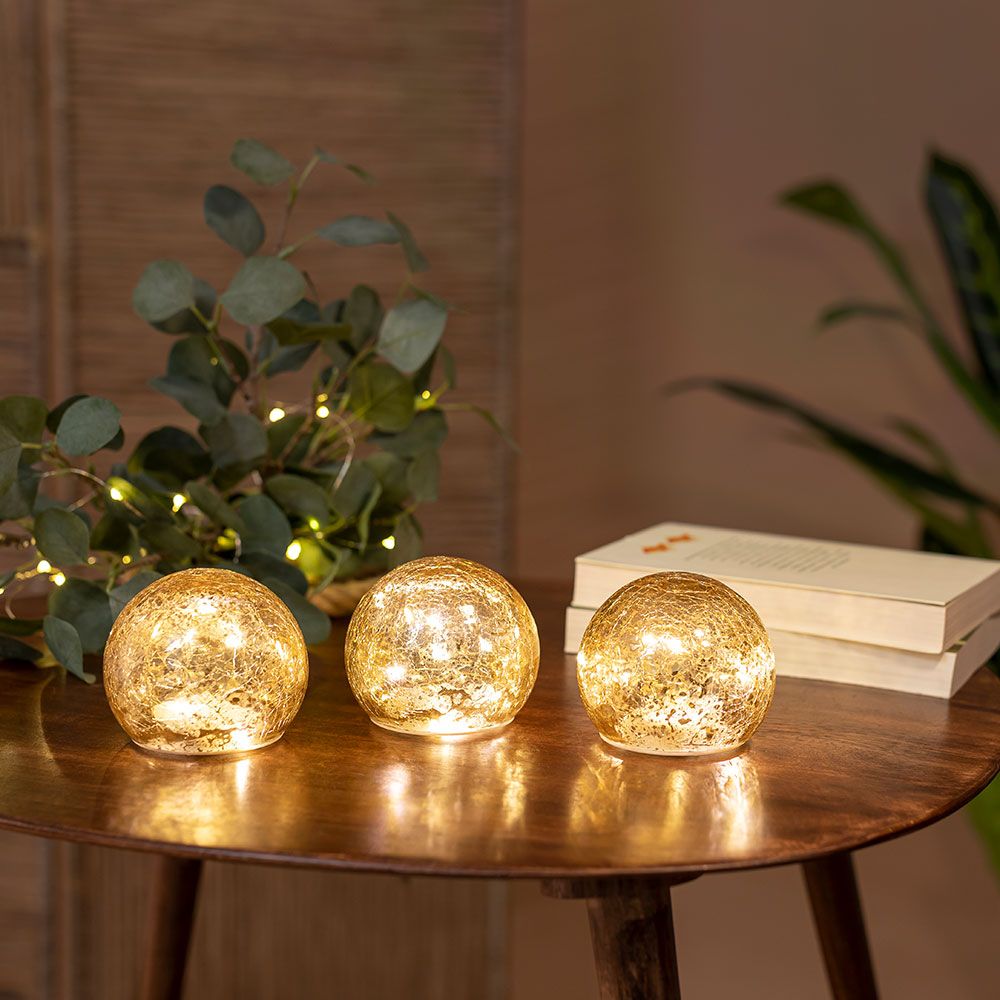 3er-Set LED Weihnachtskugeln Lua Ø 10cm auf Tisch, strahlen warmes Licht für eine festliche Atmosphäre.