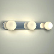 Applique miroir Azos 44 cm IP44 chromée, blanche, montée sur un mur avec trois lampes allumées.