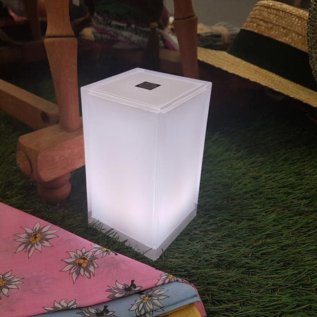 Set da 6 lampade da tavolo a batteria LED Cub con controllo tramite app, in uso su un prato con tessuti colorati.