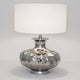 Lampe de table Damasco en aluminium nickelé argenté sur fond clair avec une forme simple.