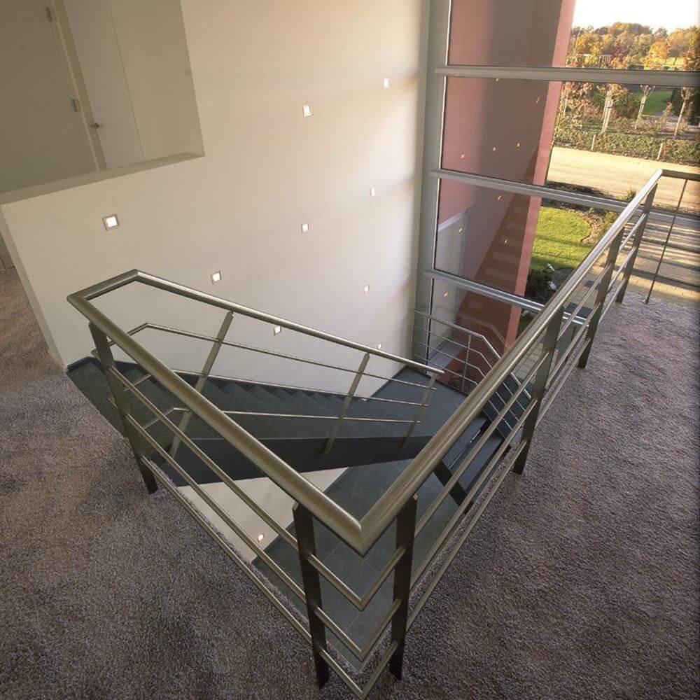 Moderne Treppenhausansicht mit grauem Teppich und Stahlgeländer.