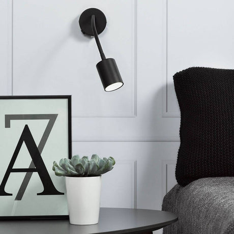 Découvrez Wandspot en noir sur un mur au-dessus d'une table avec des plantes et des cadres photo.