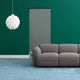 Abgerundete Pendelleuchte Norm12 XL Weiß in einem modernen Wohnraum mit grauem Sofa und grünem Wandanstrich.