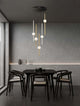 Acrobat LED Pendelleuchte 7-flammig 3000K Schwarz in modernem Essbereich mit Holzstuhl und stilvollem Design.