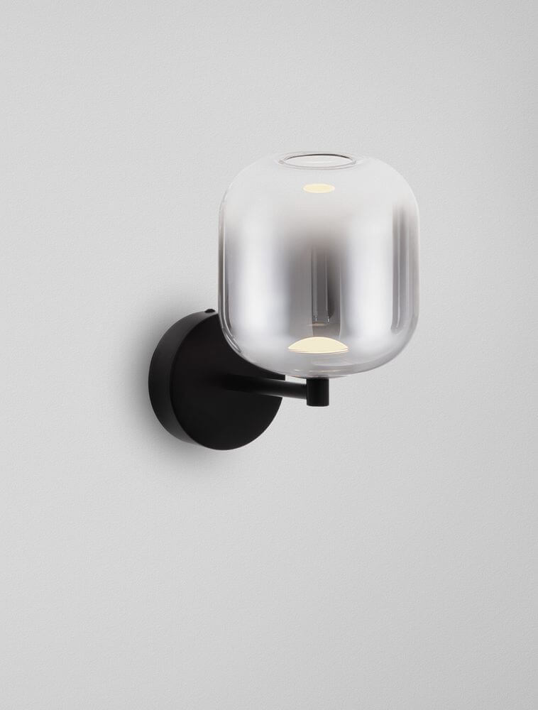 Aelia LED Wandleuchte 3000K an einer Wand, modern, elegantes Design mit rauchgrauem Glas und schwarzem Metall.