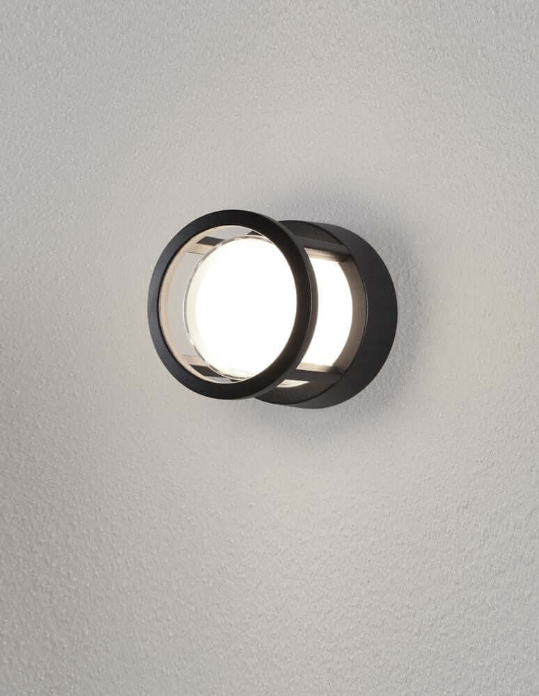 Agosto LED Außenwandleuchte Ø 11cm IP54 an einer Wand montiert, modern und elegant in schwarzem Design.
