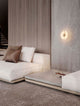 Aider Wandleuchte 3000K an Wohnzimmerwand in Goldfinish mit alabasterähnlichem Element und warmem LED-Licht