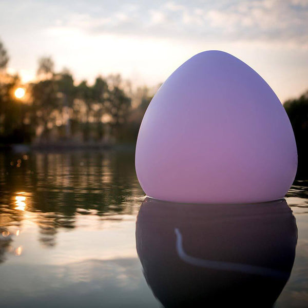Cordless LED outdoor light Stone L with app control floating in the pond at sunset.