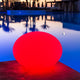 Akku LED-Designleuchte Flatball in Rot am Pool bei Sonnenuntergang, ideal für Garten und Terrasse.
