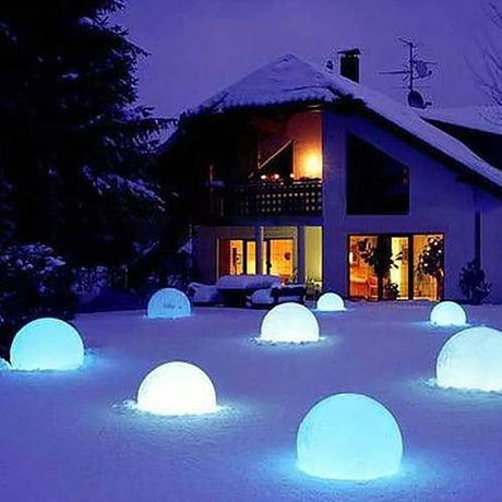 Lampe boule sur batterie LED Globe 50 cm avec commande via application brille dans la neige à côté d’une maison.