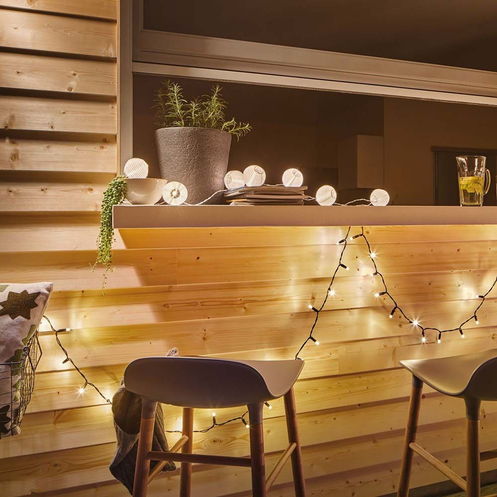 Akku LED Lampionkette in warmweißem Licht dekoriert die Holzbar für eine gemütliche Atmosphäre