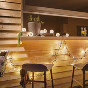 Battery LED lantern string lights IP44 3000K 7x1lm USB, warm white light accents in a cozy outdoor atmosphere.