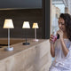 Frau genießt ein Getränk neben drei Akku LED-Tischleuchten in modernem Design auf einer Holztheke.